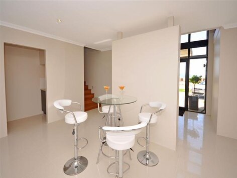 Interior entrance area with white chairs and glass table
